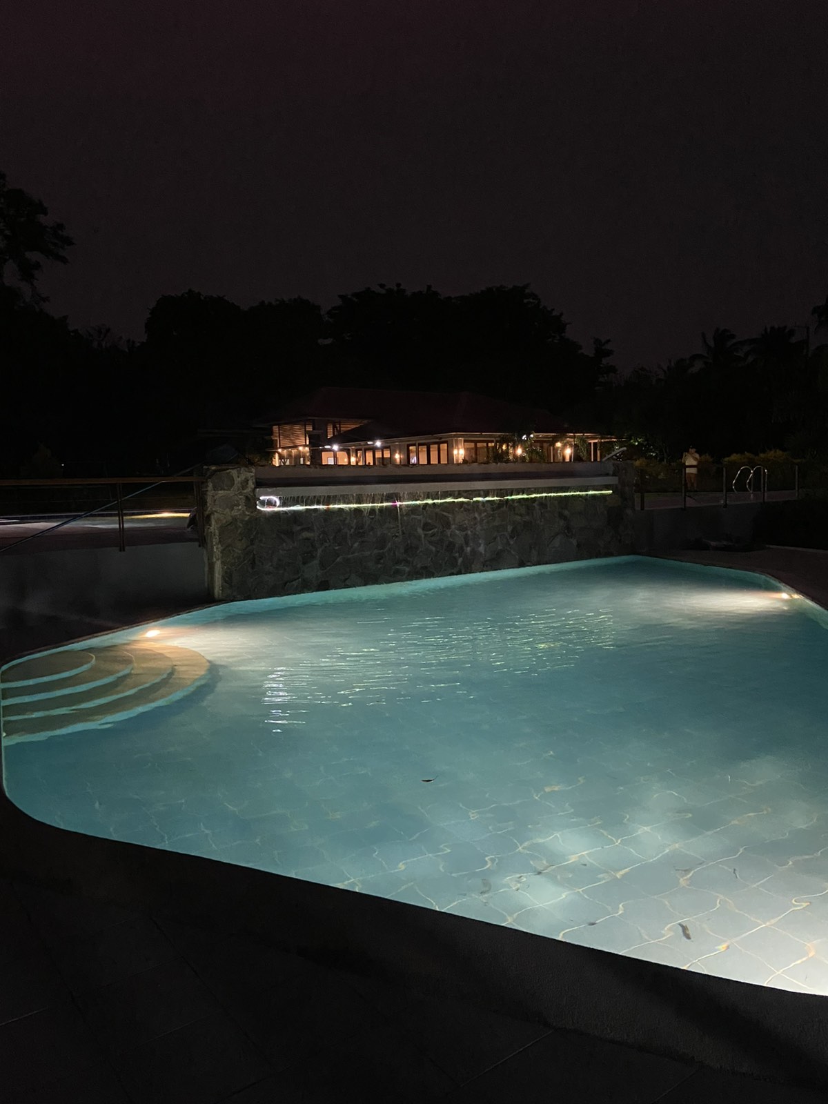 Beautiful illuminated swimming pool at night with resort backdrop